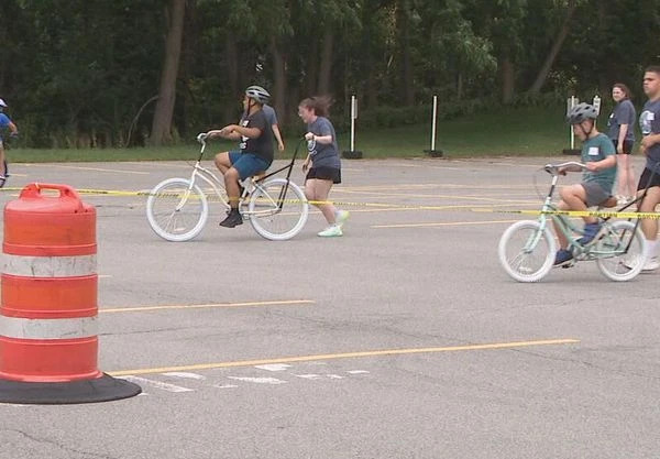 Volunteers are pushing children on balance bikes during AutismUps iCanBike camp.